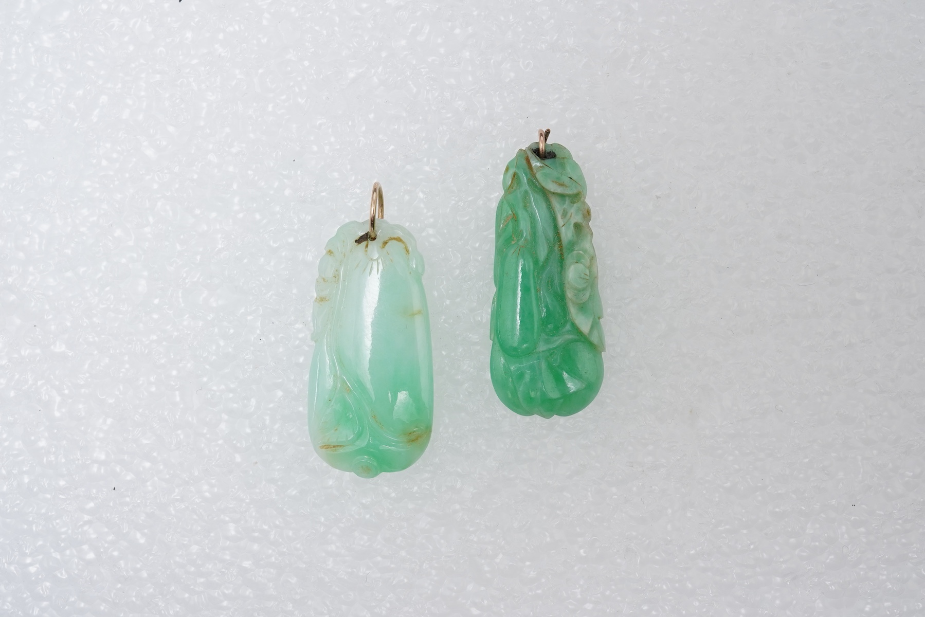 Two carved jadeite pendants, China, early 20th century, each carved to depict a fruiting vine of bitter gourd, longest 3.5cm excluding bail, combined gross weight approximately 10 grams